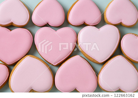 Homemade heart shaped glazed pink cookies as abstract pattern. Tasty treats for Valentine's day. View from above. 122663162