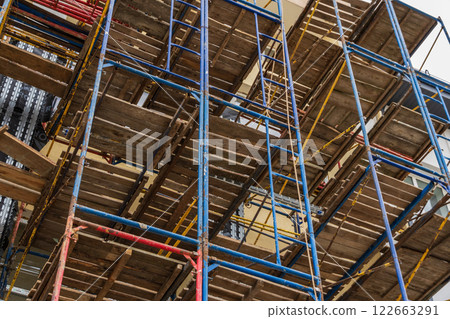 Workers assemble extensive scaffolding for the construction of a new building, highlighting industrial progress in urban development Workers assemble extensive scaffolding for the construction of a new building, highlighting industrial progress in urban development 122663291