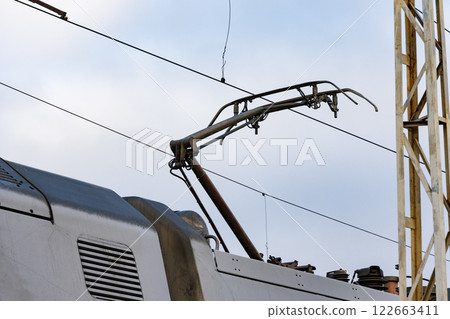 Electric train overhead conductor system seen at a railway station, highlighting modern transport infrastructure in action Electric train overhead conductor system seen at a railway station, highlighting modern transport infrastructure in action 122663411