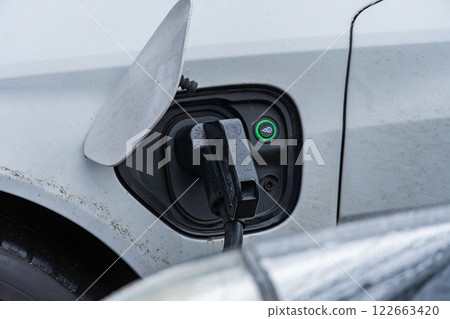 An electric vehicle is connected to a charging station, highlighting advancements in renewable energy and efficient transportation solutions An electric vehicle is connected to a charging station, highlighting advancements in renewable energy and efficient transportation solutions 122663420