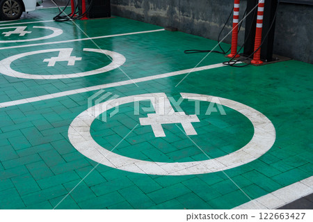 Charging points for electric cars marked on vibrant green pavement, showcasing renewable energy solutions for modern vehicles 122663427
