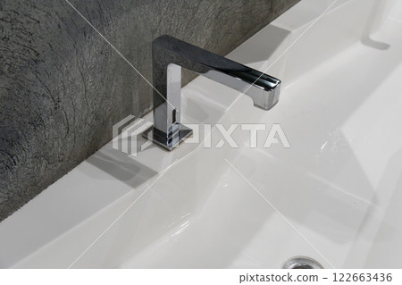 This contemporary restroom features a spacious design with a clean sink, dual faucets, and frosted glass details, perfect for urban living 122663436