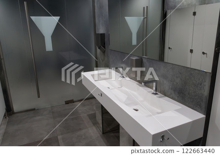 A contemporary bathroom showcases a clean, spacious design with dual sinks, sleek faucets, and frosted glass in an urban interior A contemporary bathroom showcases a clean, spacious design with dual sinks, sleek faucets, and frosted glass in an urban interior 122663440