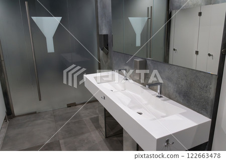 Contemporary restroom showcasing a spacious design with minimalist aesthetics, emphasizing cleanliness and functionality for public use 122663478
