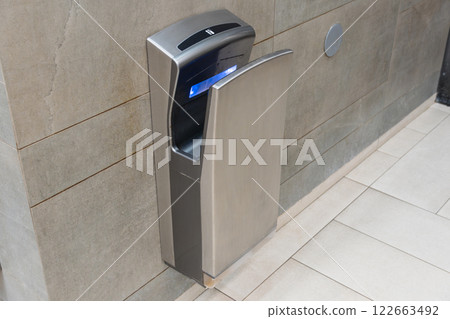Cutting-edge hand drying equipment is installed in a stylish bathroom, promoting sanitation and modern convenience for users 122663492