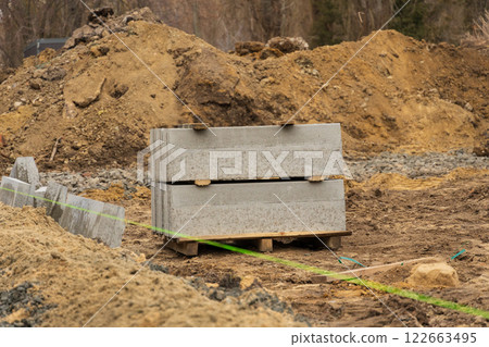 Gravel and concrete blocks rest at a construction site, highlighting ongoing repairs in an industrial area along a busy city road 122663495