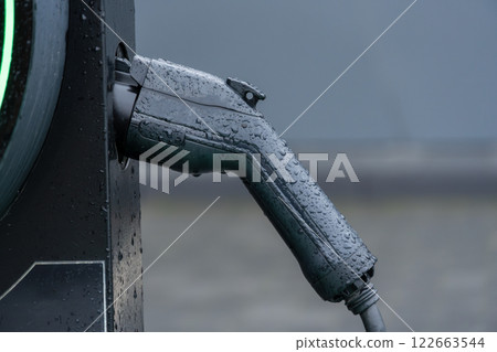 Electric vehicle charging connection at a station shows the blend of technology and sustainability as raindrops highlight the scene 122663544