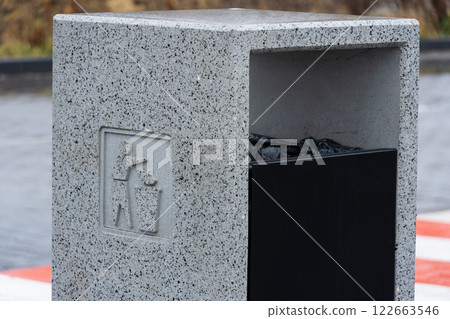 A concrete trash bin stands prominently, promoting proper waste management and recycling in an urban area, demonstrating environmental care 122663546