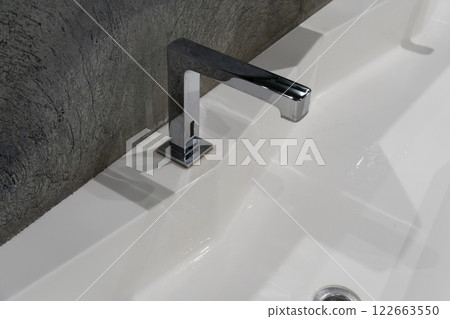 Contemporary restroom showcases a clean design with a wide sink, dual faucets, and frosted glass elements that emphasize hygiene and simplicity 122663550