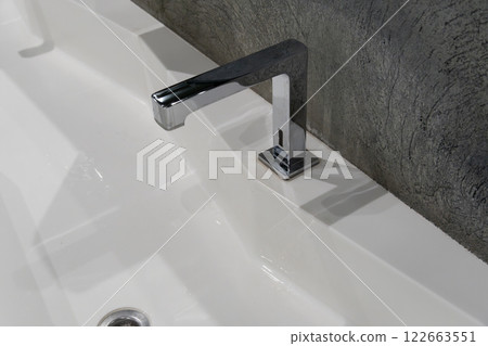 A spacious, contemporary restroom showcases a clean frosted glass sink with stylish dual faucets, emphasizing minimalist design 122663551