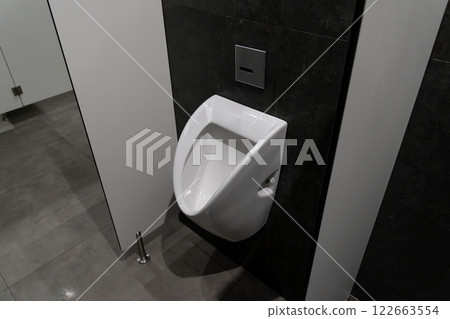 A modern restroom features a sleek urinal with a minimalist design, emphasizing hygiene and cleanliness in a public setting A modern restroom features a sleek urinal with a minimalist design, emphasizing hygiene and cleanliness in a public setting 122663554