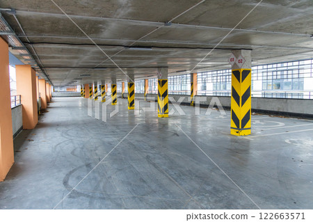 Empty parking garage with yellow and black pillars in a modern urban setting, showcasing clean lines and contemporary design elements 122663571