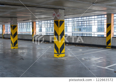 Spacious parking garage with designated spots and safety markers, providing secure vehicle storage in a contemporary urban environment Spacious parking garage with designated spots and safety markers, providing secure vehicle storage in a contemporary urban environment 122663572