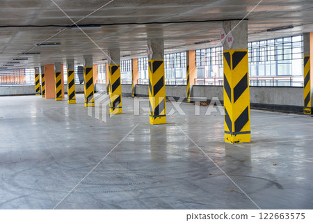 Spacious underground parking area featuring yellow and black striped columns, designed for efficient vehicle storage and easy access Spacious underground parking area featuring yellow and black striped columns, designed for efficient vehicle storage and easy access 122663575