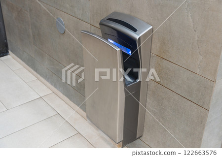 An automatic hand dryer installed in a contemporary bathroom setting promotes hygiene and efficiency for users after washing hands An automatic hand dryer installed in a contemporary bathroom setting promotes hygiene and efficiency for users after washing hands 122663576