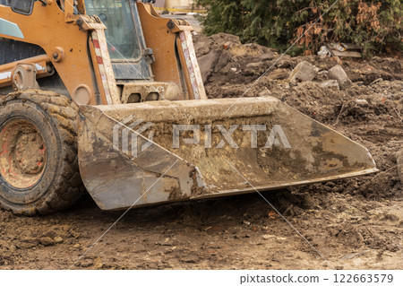 Backhoe operates at a construction site, efficiently digging and preparing the ground for new infrastructure development and engineering tasks 122663579