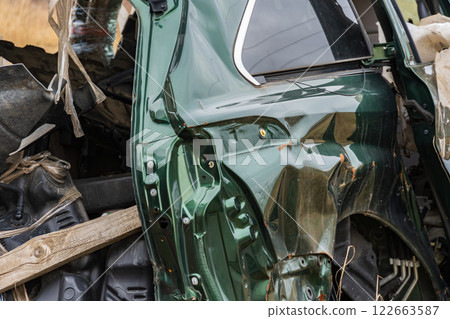 A wrecked car lies in a rural location, showcasing extensive damage to the side panel and highlighting transportation dangers and insurance concerns 122663587