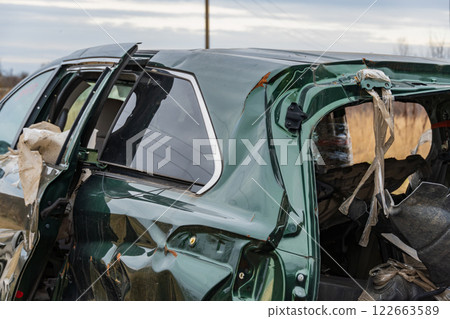 A wrecked car with severe damage to its roof and side is observed in a rural environment, highlighting the dangers of road incidents A wrecked car with severe damage to its roof and side is observed in a rural environment, highlighting the dangers of road incidents 122663589