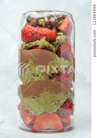 Close up Dubai chocolate strawberry cup with kunafa, pistachio paste, tahini, chocolate and fresh strawberries. Vertical photo. Copy space. Sweets and desserts, take away street food. 122664499