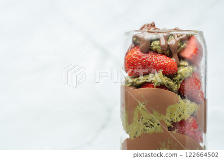 Close up of Dubai chocolate strawberry cup with kataifi, pistachio paste, tahini, chocolate and fresh strawberries. Copy space for text. Sweets and desserts, take away street food. Close up of Dubai chocolate strawberry cup with kataifi, pistachio paste, tahini, chocolate and fresh strawberries. Copy space for text. Sweets and desserts, take away street food. 122664502