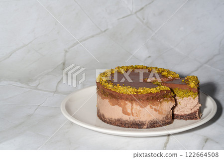 Sliced chocolate Dubai cheesecake with pistachio paste and kataifi dough filling covered in chocolate ganache on white plate. White background copy space. Indulgence, gourmet desserts, art of culinary 122664508