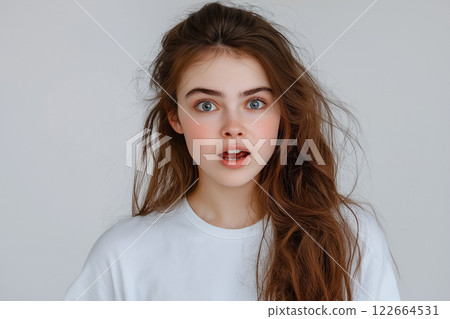 A professional studio portrait of a girl on a light background, her face lit up with surprise and wide-open eyes A professional studio portrait of a girl on a light background, her face lit up with surprise and wide-open eyes 122664531