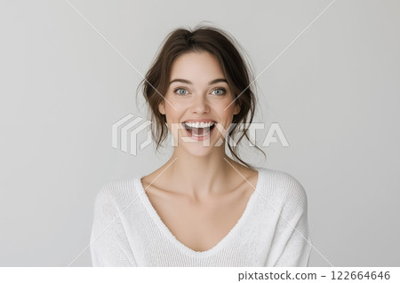 A studio portrait of a woman showing excitement, with wide eyes and an open smile 122664646