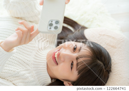 一名日本女性仰臥操作智慧型手機 122664741