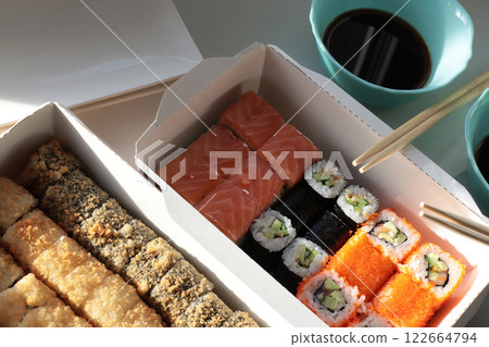 fish bun and sushi set breaded rice japanese cuisine japanese food delivery bright buns hand chopsticks with roll california philadelphia white dishes soy saucehands holding chopsticks 122664794