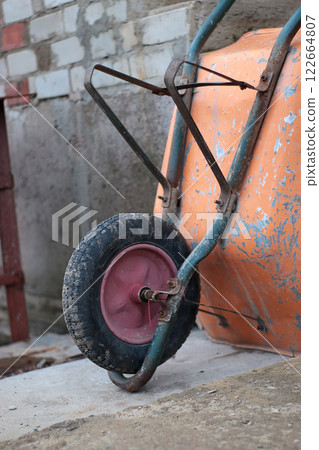 orange wheelbarrow with two handles and one wheel, construction, repair, construction site, house construction, foundation, concrete, DIY construction, metal containers, garbage transportation orange wheelbarrow with two handles and one wheel, construction, repair, construction site, house construction, foundation, concrete, DIY construction, metal containers, garbage transportation 122664807