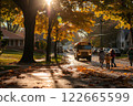Children walking toward a school bus on a suburban street surrounded by autumn trees with golden leaves and warm morning sunlight 122665599