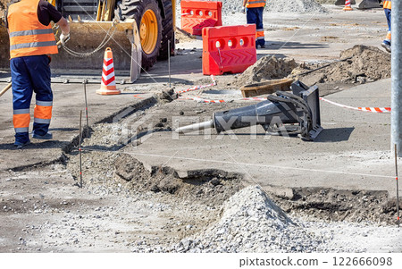 Construction workers actively repairing roads and using heavy machinery in urban area 122666098