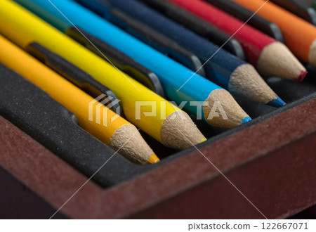 Close-up of multi colored pencils or wooden crayons to each other arranged in a neat row in wooden pencil case. 122667071