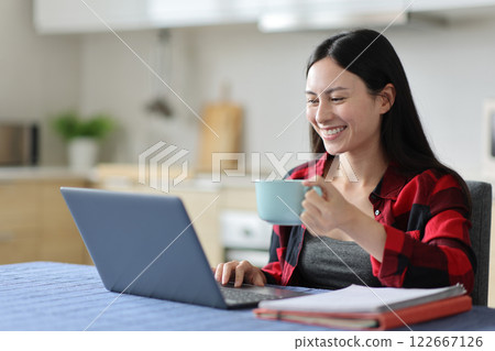 Happy asian woman drinking and e-learning using laptop 122667126