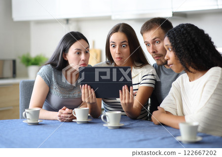 Perplexed group of friends checking tablet 122667202