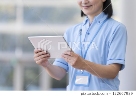 Image of a middle-aged woman holding a tablet, a facility staff member Image of a middle-aged woman holding a tablet, a facility staff member 122667989