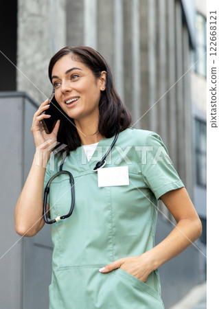 Young female doctor talking on the phone with a patient and looking involved and friendly 122668121
