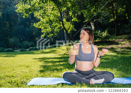 Young woman on a third pregnancy trimester having her lunch in the park Young woman on a third pregnancy trimester having her lunch in the park 122668163