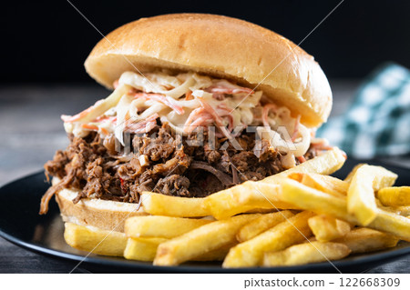 Pulled pork sandwich with coleslaw and french fries on wooden table 122668309