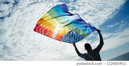 LGBTIQ person waves a rainbow US flag on the sky LGBTIQ person waves a rainbow US flag on the sky 122668451