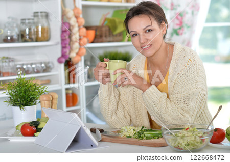 Beautiful happy woman coocking salad on kitchen 122668472
