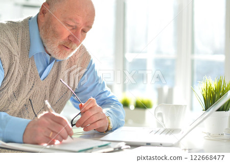 Portrait of an elderly man using a laptop in an office Portrait of an elderly man using a laptop in an office 122668477