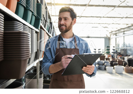 Male garden center worker in plants pot department making notes 122668812