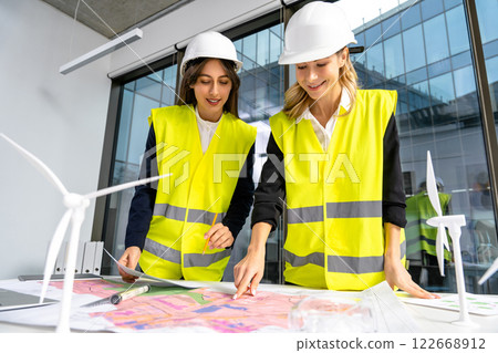 Group of engineers discussing new wind power project and looking involved Group of engineers discussing new wind power project and looking involved 122668912