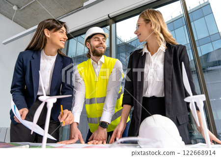 Group of engineers discussing new wind power project and looking involved Group of engineers discussing new wind power project and looking involved 122668914