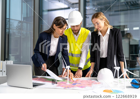 Group of engineers discussing new wind power project and looking involved Group of engineers discussing new wind power project and looking involved 122668919