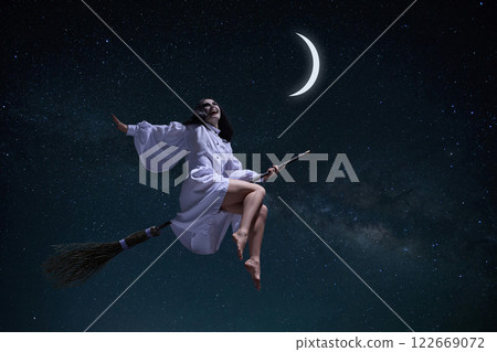 Laughing woman in white gown, mystical witch flying on broomstick with moon and dark night starry sky. Laughing woman in white gown, mystical witch flying on broomstick with moon and dark night starry sky. 122669072