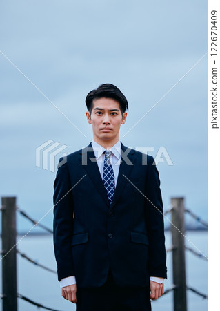 Young man in suit looking at camera, sky 122670409