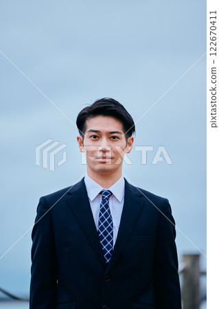 Young man in suit looking at camera, sky Young man in suit looking at camera, sky 122670411