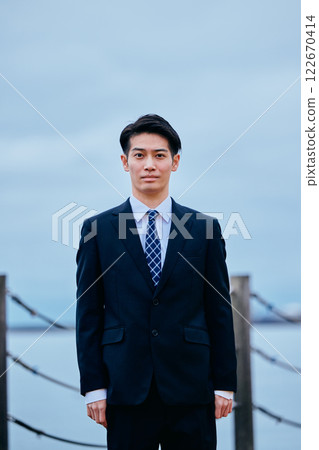 Young man in suit looking at camera, sky 122670414